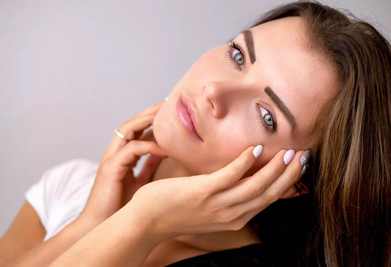 A woman caresses her face showing off her clear skin.
